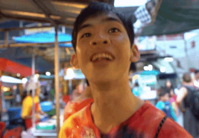 a young man in a tie dye shirt smiles in a crowded area