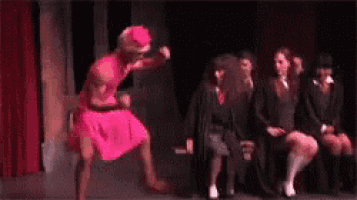 a woman in a pink dress is dancing in front of a group of girls
