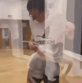 a man wearing headphones and a t-shirt that says freedom is standing in front of a glass wall .