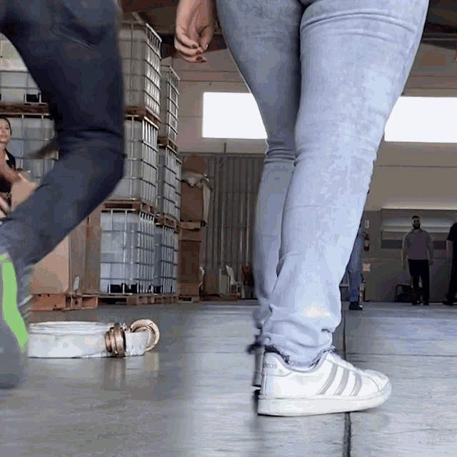 a person wearing a pair of adidas shoes stands in a warehouse