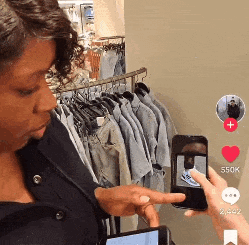 a woman taking a picture of a man 's shoes with a phone that has 550k followers
