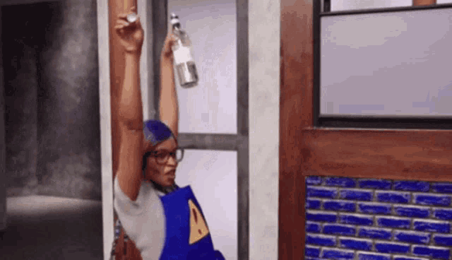 a person in a blue apron with an a on it is holding a bottle over their head