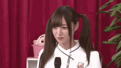 a young woman with pigtails is standing in front of a microphone .
