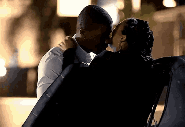 a man and woman are kissing in the back of a car at night .