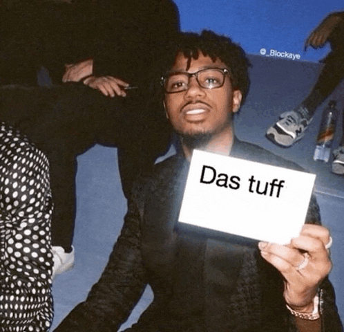 a man holds up a card that says das tuff