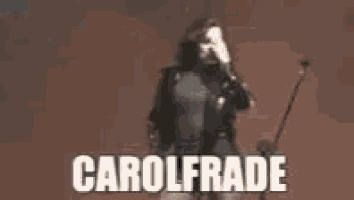 a woman in a black jacket is standing in front of a microphone with the name carol frade on the bottom