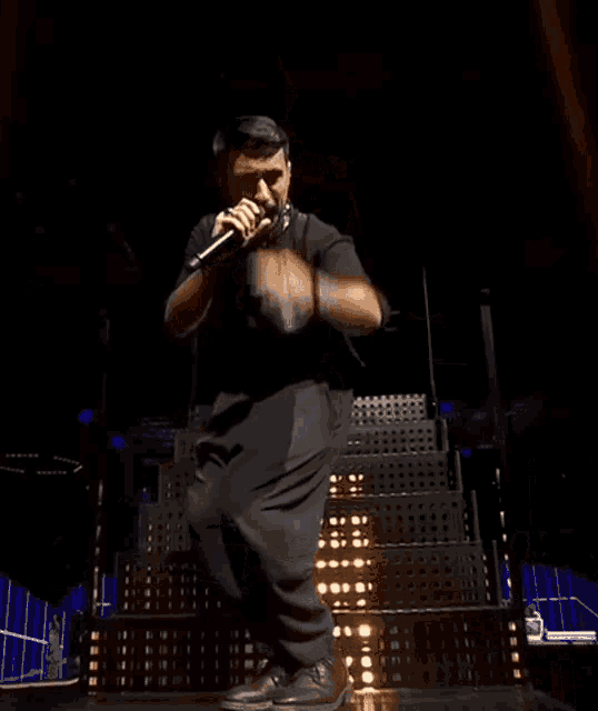 a man singing into a microphone with his hands in the air