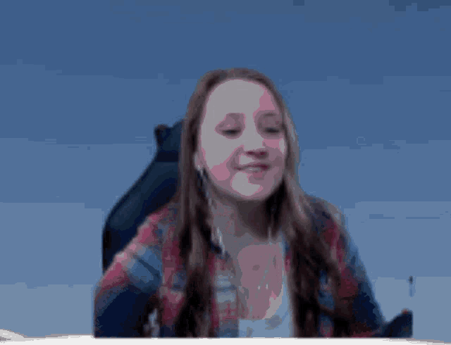 a woman in a plaid shirt is sitting in a chair with a blue sky in the background