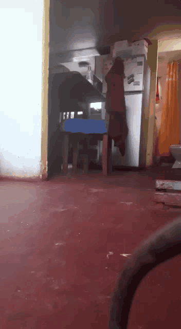 a room with a refrigerator and a table with a blue table cloth on it