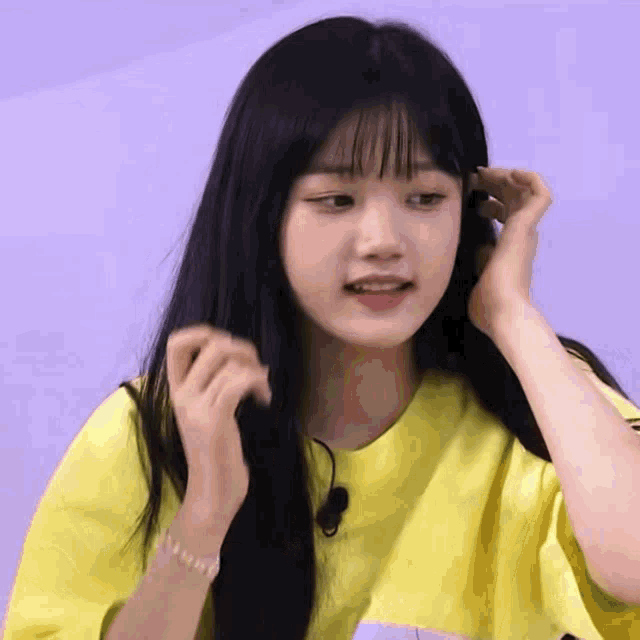 a young girl with long black hair is wearing a yellow t-shirt .