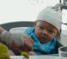 a baby wearing a hat is sitting in a high chair .