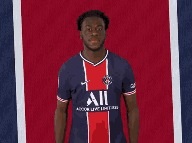 a soccer player is pointing up with his fingers while wearing a blue and red jersey .