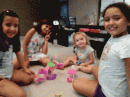 a group of young girls sitting on the floor with toys