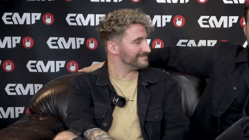 a man is sitting in front of a wall that says emp