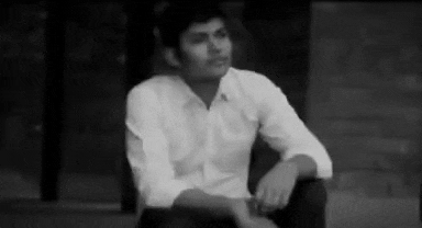 a black and white photo of a man in a white shirt sitting on the ground .