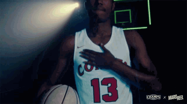 a basketball player with the number 13 on his jersey holds a basketball