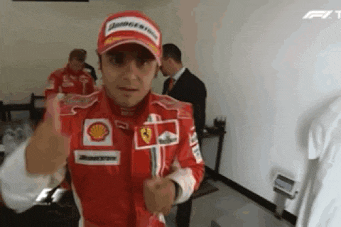 a man in a red and white ferrari uniform is giving a thumbs up .