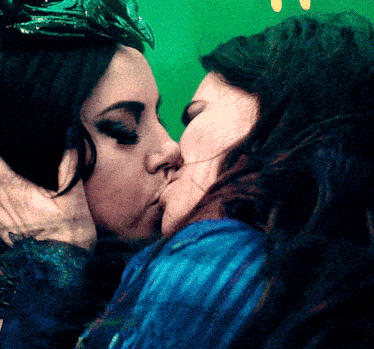 two women kissing in front of a green screen