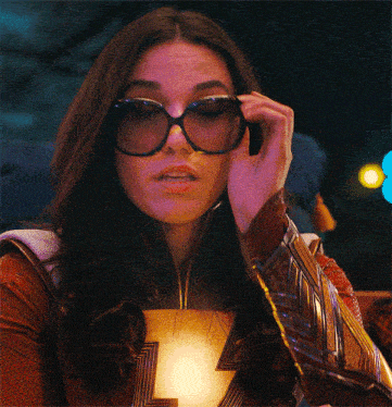 a woman adjusts her sunglasses while wearing a costume with the letter z on it