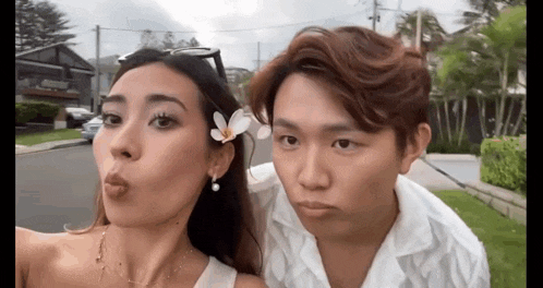 a man and a woman are standing next to each other making funny faces .