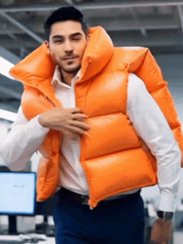 a man is wearing a large orange vest on his back