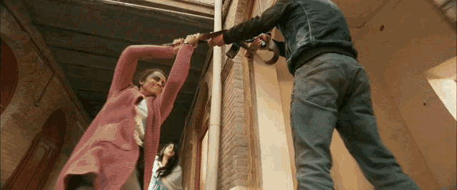 a man and a woman are fighting with guns in a building