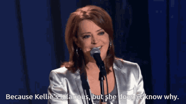 a woman speaking into a microphone with the words because kellie 's hilarious