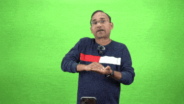 a man wearing a blue tommy hilfiger sweater stands in front of a green background