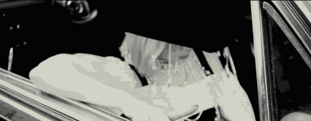 a woman in a white dress is sitting in a car with her head out the window .
