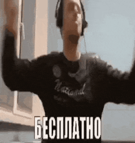 a man wearing headphones is standing in front of a window with his arms outstretched .