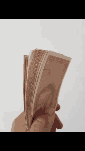 a hand is holding a stack of money that says ' united states of america ' on the back