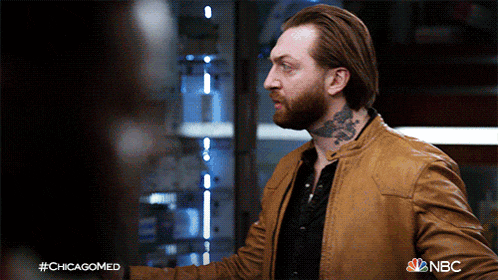 a man with a tattoo on his neck is wearing a brown leather jacket with nbc written on the bottom