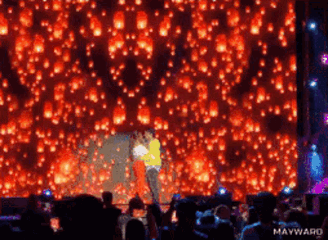 a couple kissing on a stage with lanterns falling from the sky