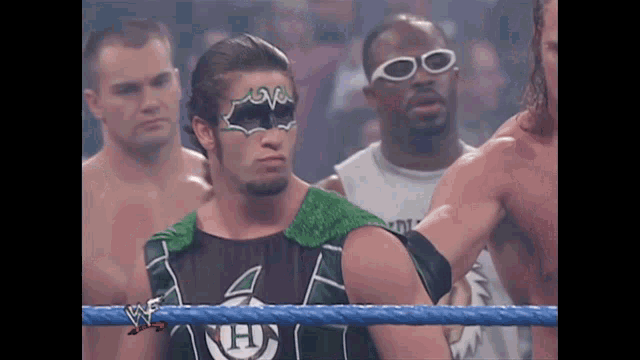 a wrestler wearing sunglasses and a mask with the letter h on his shirt