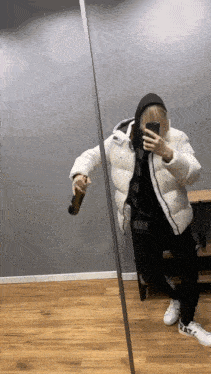 a person in a white jacket is taking a picture of themselves in a mirror