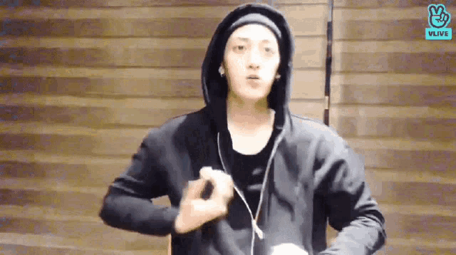 a man in a black hoodie is making a peace sign with his hand .