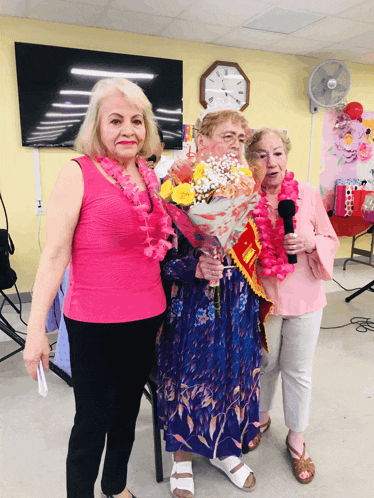 a woman in a pink tank top holds a bouquet of flowers while standing with two other women