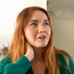 a woman with long red hair is wearing a green sweater and a necklace .