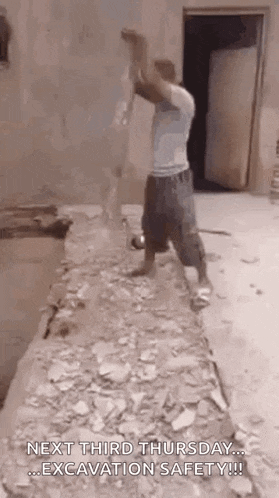 a man is standing in a room with a hammer in his hand .