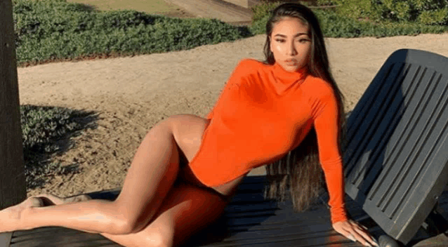 a woman in an orange bodysuit is sitting on a chair .