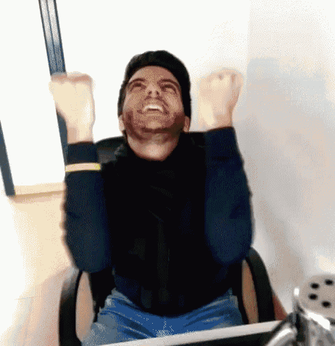 a man with a beard is sitting in an office chair with his arms in the air