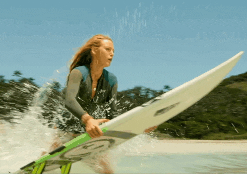 a woman in a wetsuit is holding a surfboard with the letter g on it