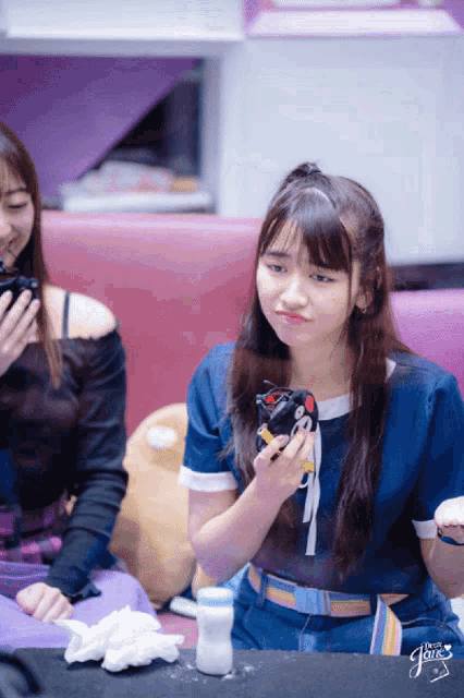 a girl in a blue shirt is holding a cat toy in her hand and the word " the girl " is on the bottom