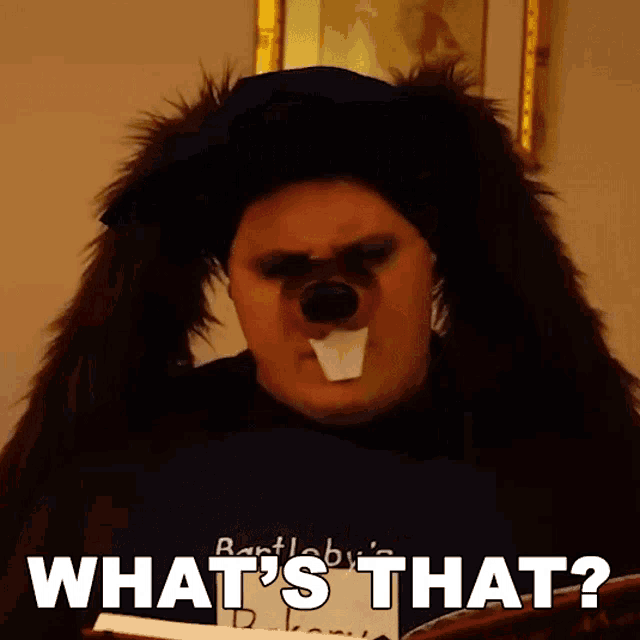 a man in a bear costume is holding a book and asking what 's that