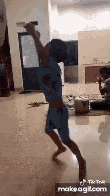 a boy is dancing in a living room with a bottle in his hand