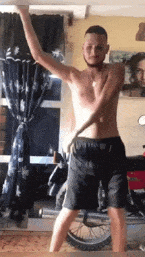 a shirtless man is standing in front of a motorcycle in a living room .