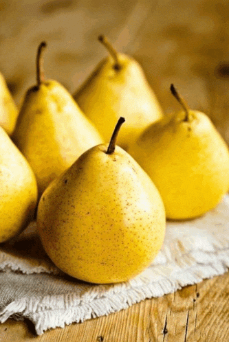 a bunch of yellow pears are sitting on a cloth