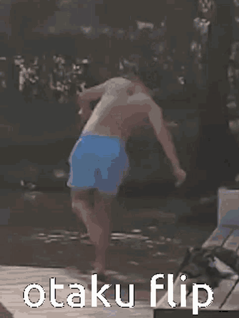 a man in blue shorts is jumping into a body of water with the words otaku flip below him .