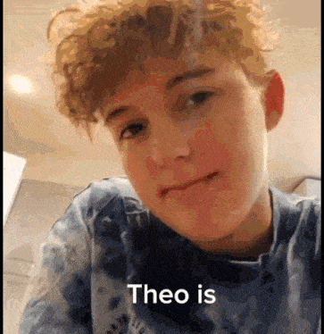 a young boy with curly hair is wearing a blue tie dye shirt and making a funny face .