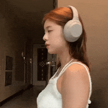 a woman wearing headphones in a hallway with her eyes closed